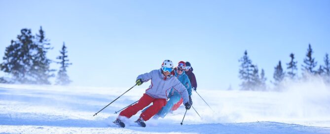 Row of male and female skiers skiing down snow covered ski slope, Aspen, Colorado, USA