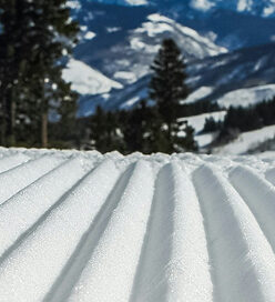 Snow-covered terrain with groomed ski tracks, surrounded by pine trees and mountains at Beaver Creek Resort, highlighting winter sports and skiing opportunities.