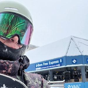Snowboarder in helmet and goggles at Vail's Born Free Express 8 lift, showcasing winter sports excitement and ski culture.