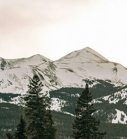Snow-capped mountains in Colorado's Rocky Mountains, showcasing winter scenery relevant to outdoor activities like skiing and biking at Beaver Creek and Breckenridge.