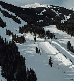 Aerial view of snowy slopes and ski lifts at Copper Mountain, showcasing winter sports terrain and surrounding pine forests.