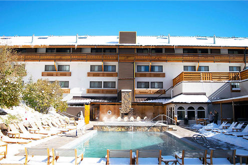 Ski lodge exterior with heated outdoor pool, snow-covered surroundings, and wooden deck chairs, emphasizing winter sports accommodations in Colorado.