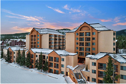 Copper Mountain resort buildings surrounded by snow and trees at sunset, showcasing ski rental locations in Colorado.