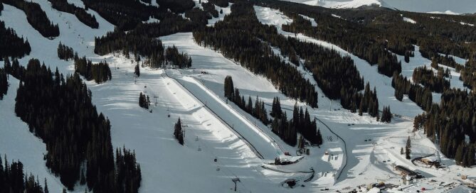 Aerial view of snowy Copper Mountain ski slopes with evergreen trees and ski lift, showcasing winter sports terrain for families and ski enthusiasts.