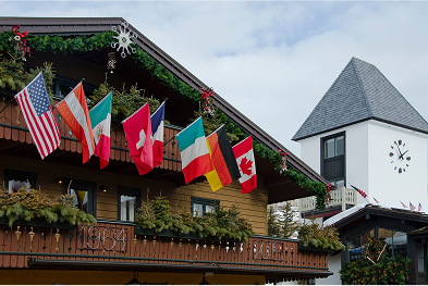 Building exterior adorned with international flags, including the United States, Canada, and several European nations, set against a cloudy sky, representing the welcoming atmosphere of Beaver Creek, Colorado, a popular destination for winter sports.