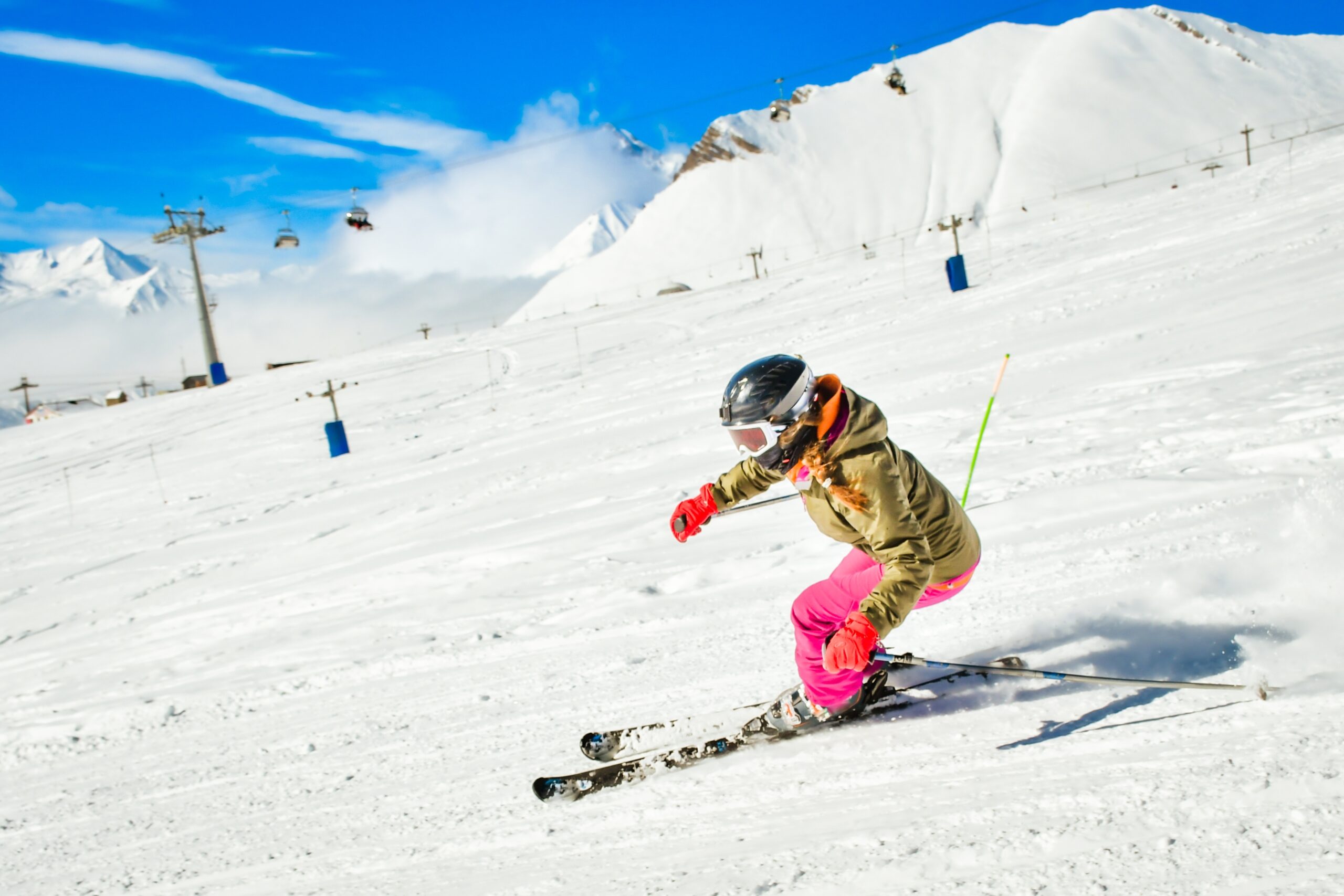 Skier carving through fresh snow on a mountain slope, showcasing vibrant ski attire and dynamic movement, representing the exhilarating experience of skiing available through Charter Sports rental services.