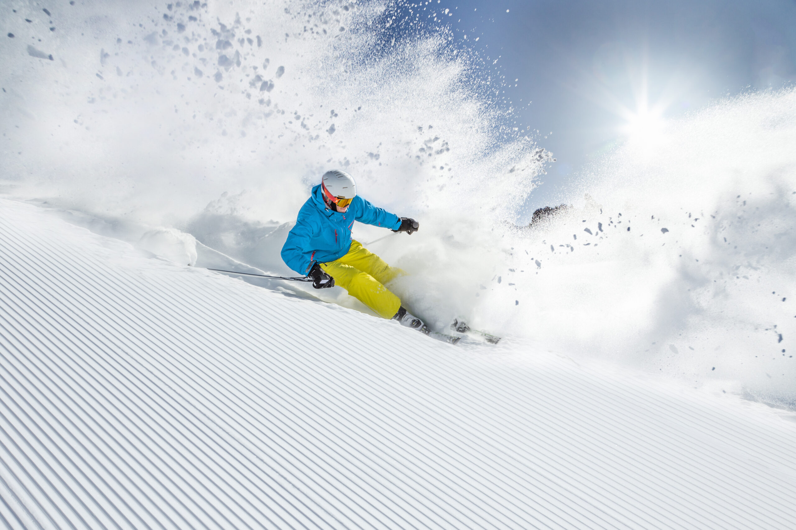 Skier in blue jacket and yellow pants carving through fresh powder snow at Copper Mountain, showcasing a thrilling skiing experience.