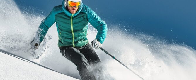 Skier in turquoise jacket carving through fresh powder snow at Beaver Creek Resort, emphasizing luxury skiing experience.