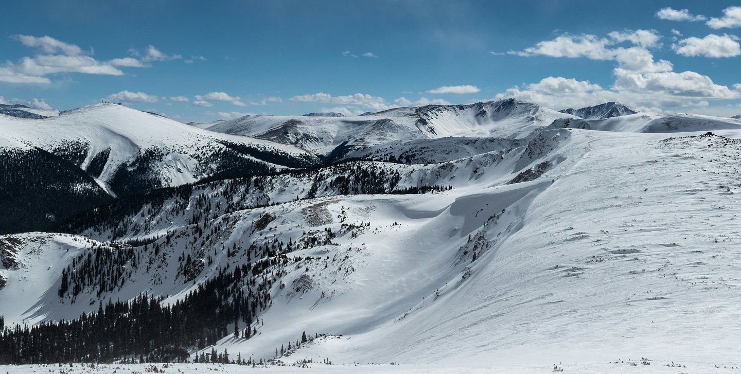 Snow-covered mountain landscape in Colorado, showcasing peaks and valleys, ideal for skiing and outdoor activities.