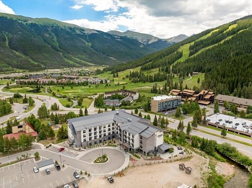 Aerial view of the Cambria Hotel in Copper Mountain, surrounded by lush green mountains and ski slopes, highlighting its location near Colorado ski resorts.